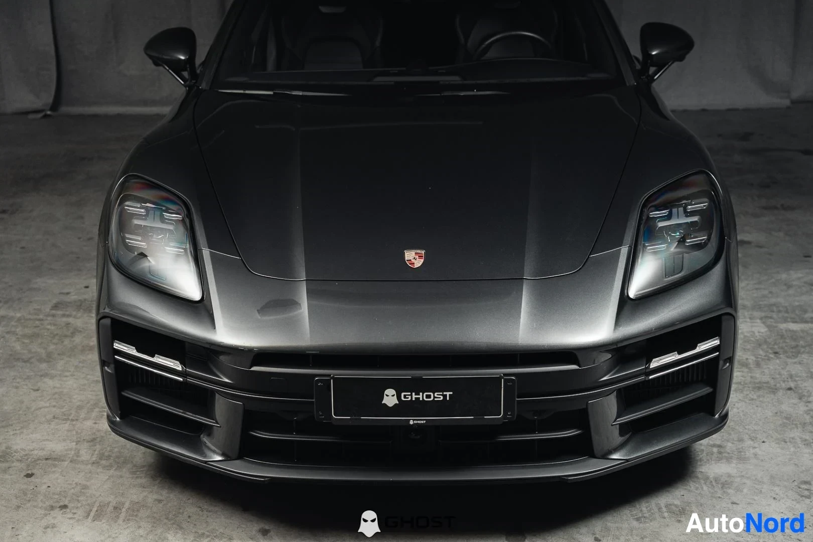 Edestä: Tummanharmaa Porsche Panamera, lähikuva keulasta, LED-ajovalot ja Porsche-merkki