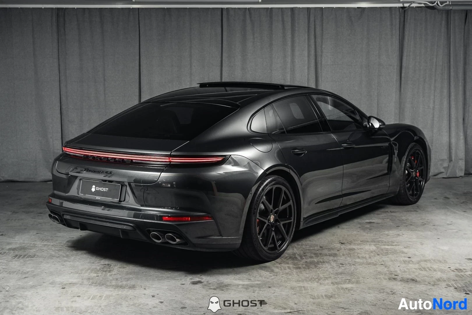 Takaviisto: Tummanharmaa Porsche Panamera, koko ajoneuvo näkyvissä, koko leveyden takavalopalkki, studiotausta