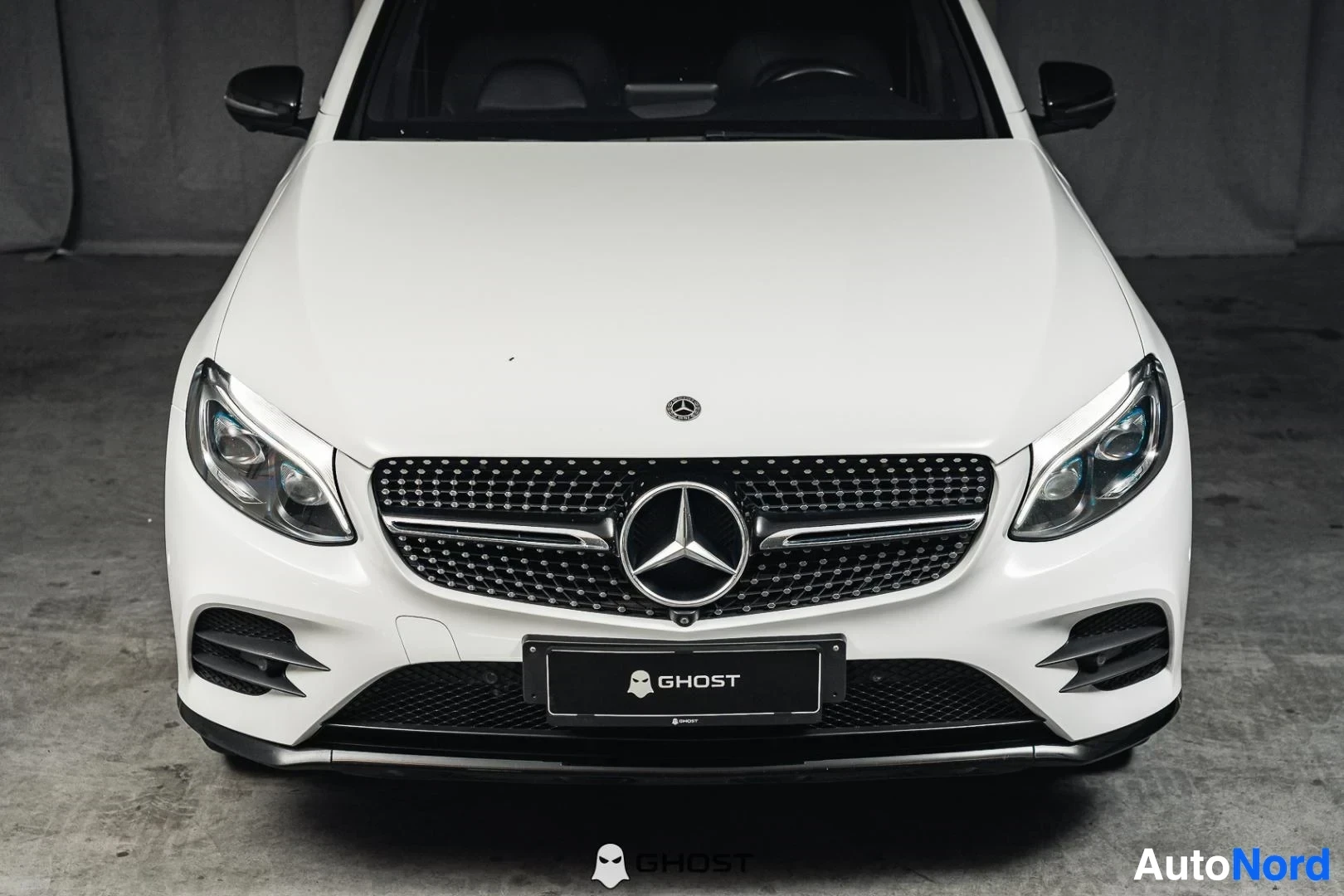 Edestä: Valkoinen Mercedes-Benz GLC 350e coupé, lähikuva keulasta, ajovalot ja timanttisäleikkö