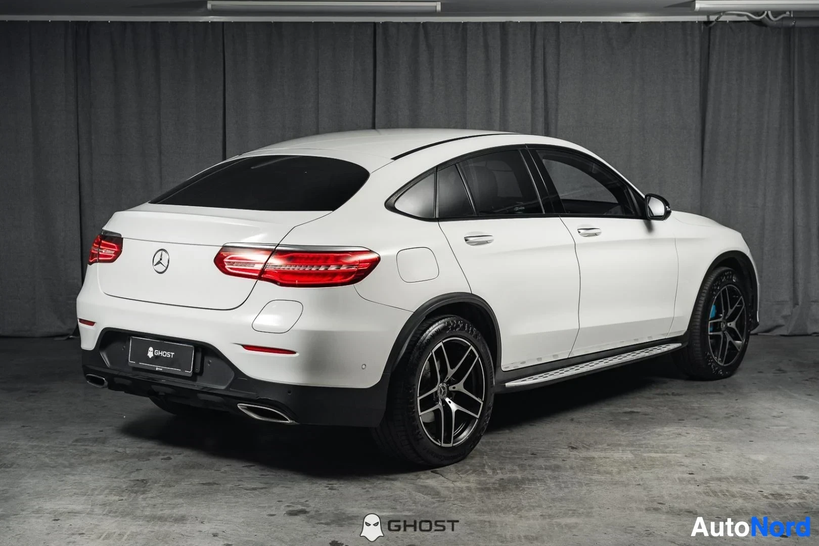 Takaviisto: Valkoinen Mercedes-Benz GLC 350e coupé, koko ajoneuvo näkyvissä, coupémainen takaosa, studiotausta