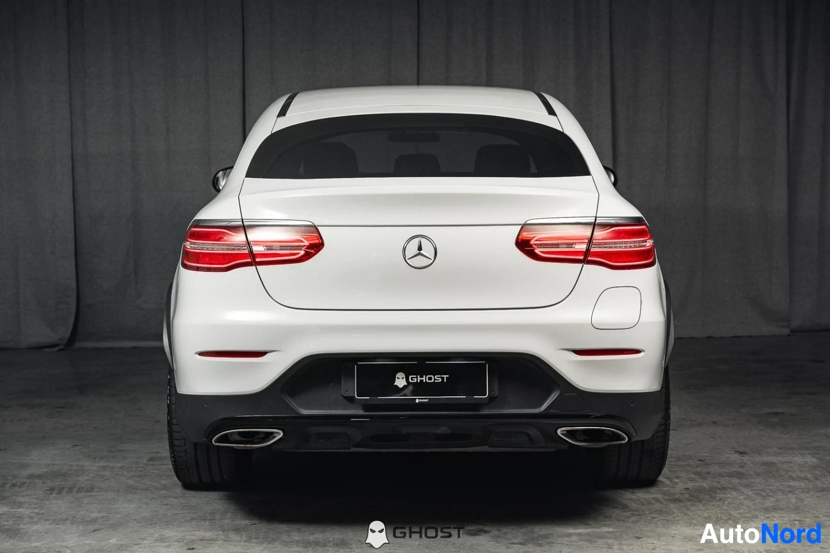 Takaa: Valkoinen Mercedes-Benz GLC 350e coupé, koko ajoneuvo näkyvissä, takavalot päällä, studiotausta