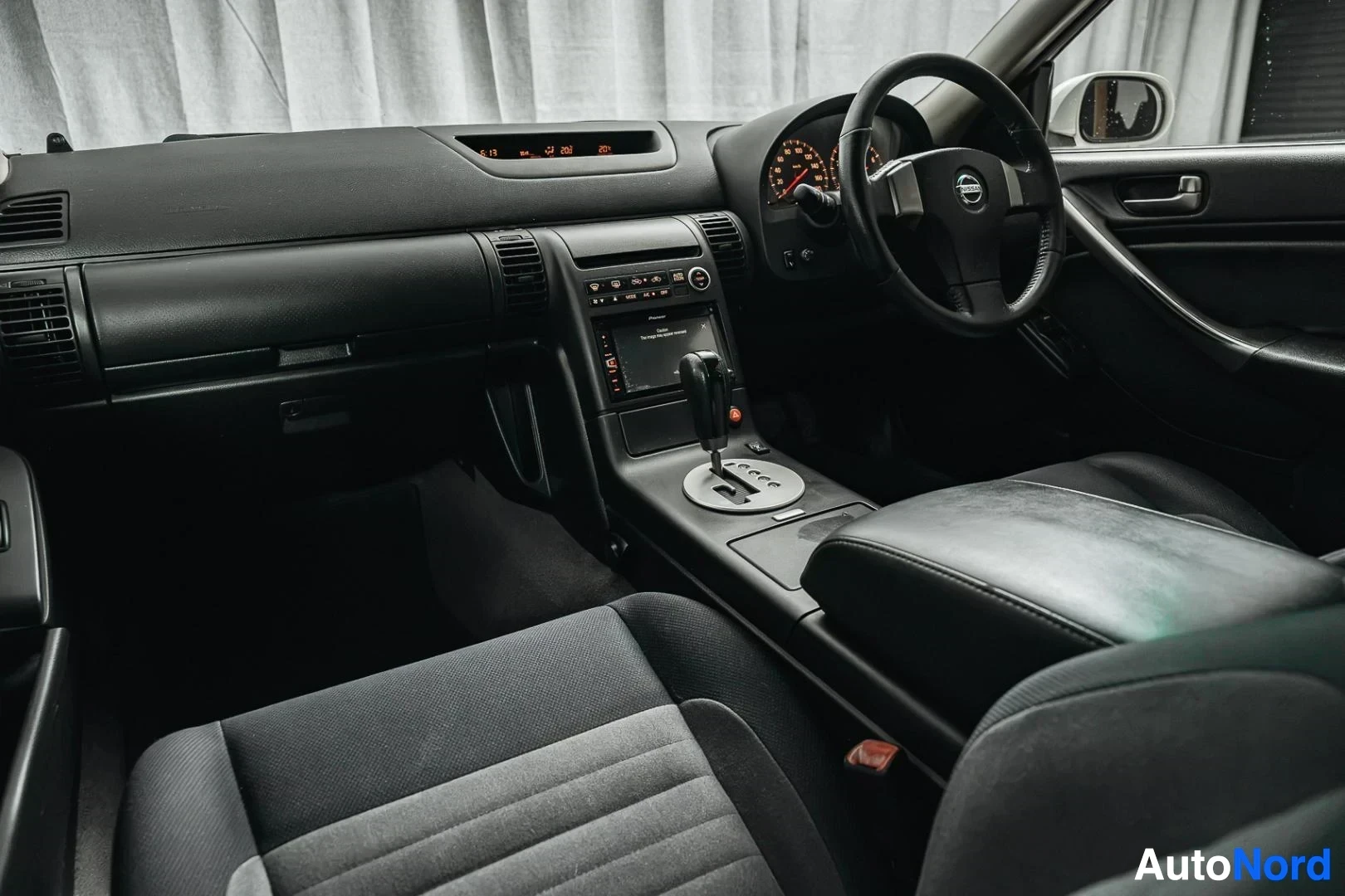 Ohjaamo: Valkoinen Nissan Stagea, kojelauta ja etuistuimet matkustajan puolelta
