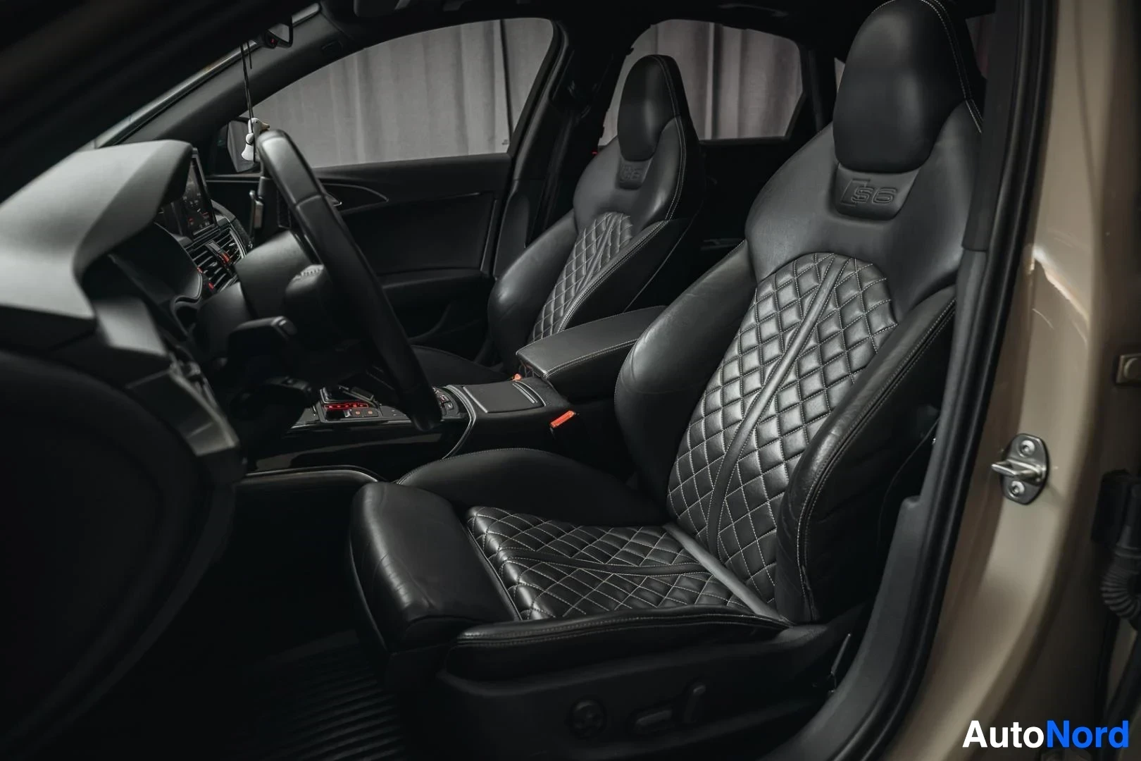 Etuistuimet: Beige Audi S6, mustat tikatut nahkaiset urheiluistuimet avoimesta ovesta kuvattuna