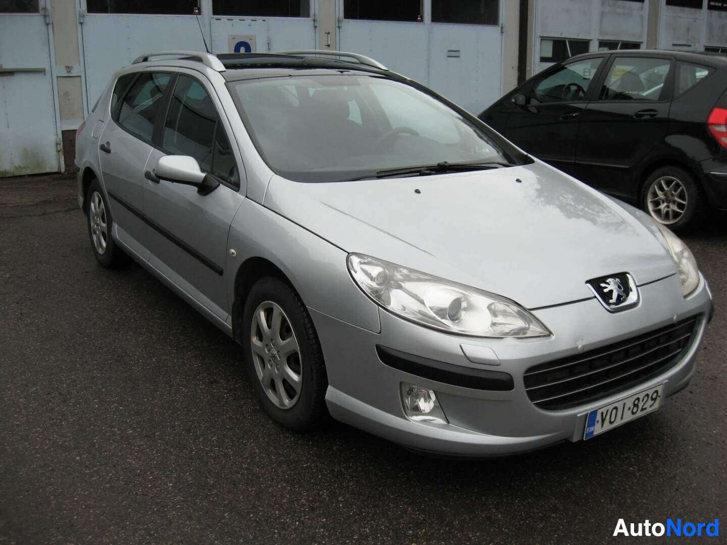 Etuviisto, nokka oikealle: Valkoinen Peugeot 407 farmari edestä, rekisterinumero VO1-829, Peugeot-logo kilvessä
