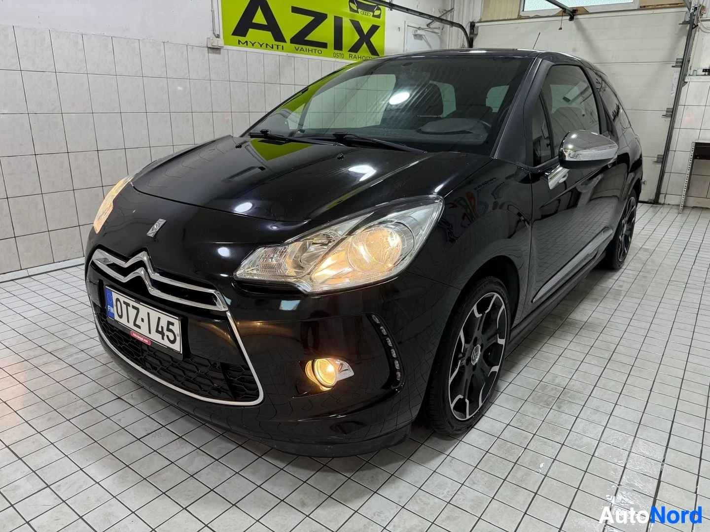 Etuviisto, nokka vasemmalle: Musta Citroën DS3 pienauton etunäkymä vasemmalta, rekisterikilvessä, valkoiset LED-ajovalot, harmaa peili, sileä musta pinta