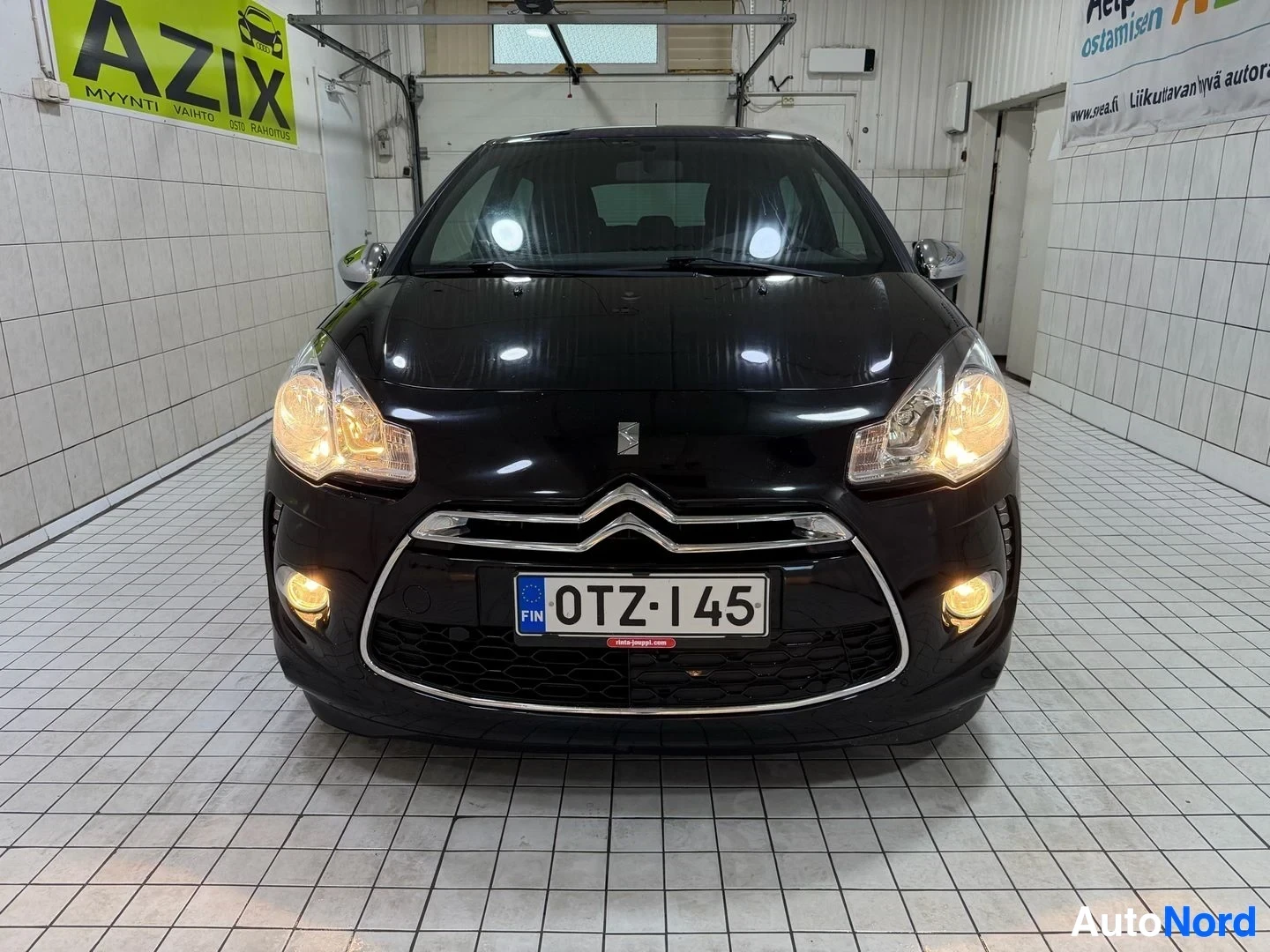 Edestä: Musta Citroën DS3 suoraan edestä katsottuna, rekisterikilvessä, kaksoisomamuotoinen valkoinen kaarina etuosassa, keltaiset ajovalot