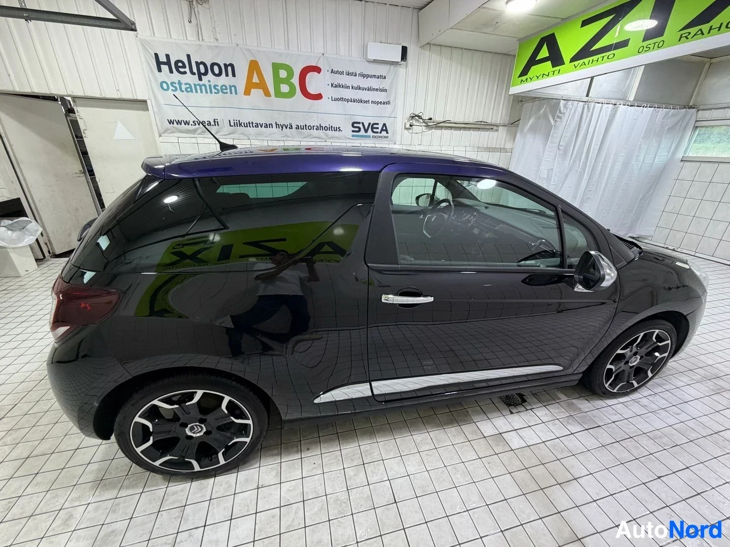 Sivulta: Musta Citroën DS3 pysäköitynä autotalliin sivuprofiilista, näkyvissä koko ajoneuvo vasemmalta puolelta, rekisterikyltti näkyy osittain, takaovi auki