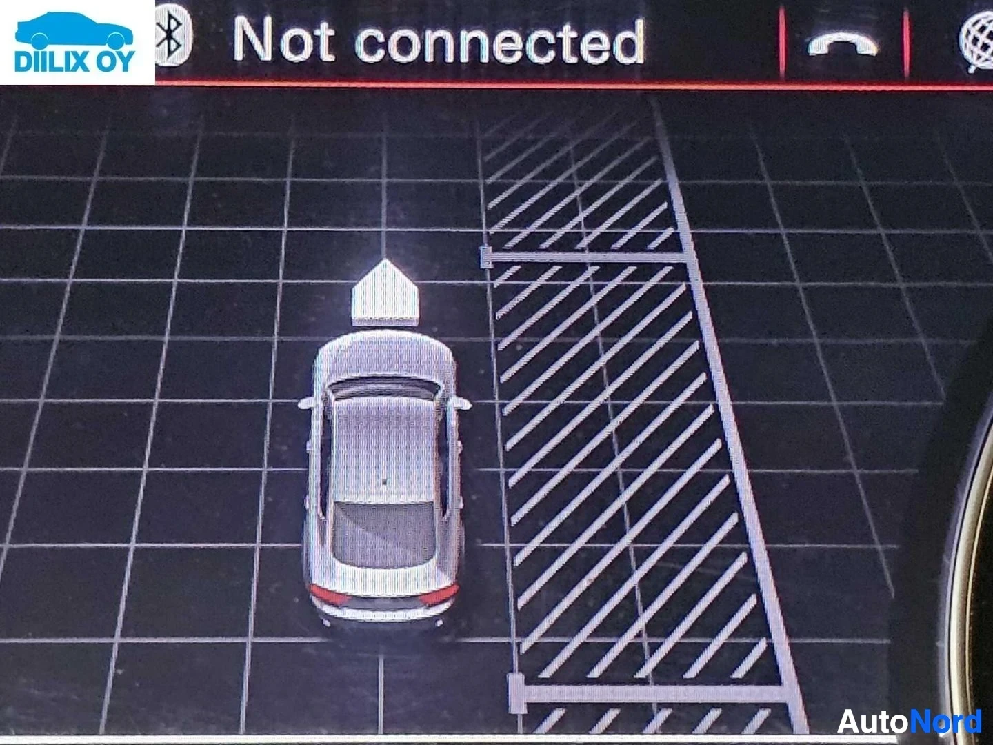 Yksityiskohta: Autojen pysäköintiavustinjärjestelmän näkymä ohjauspaneelilla, jonka näytössä näkyy yläkatsanto-näkymä ja auto pysäköintialueella. Bluetooth-symboli näkyvissä.