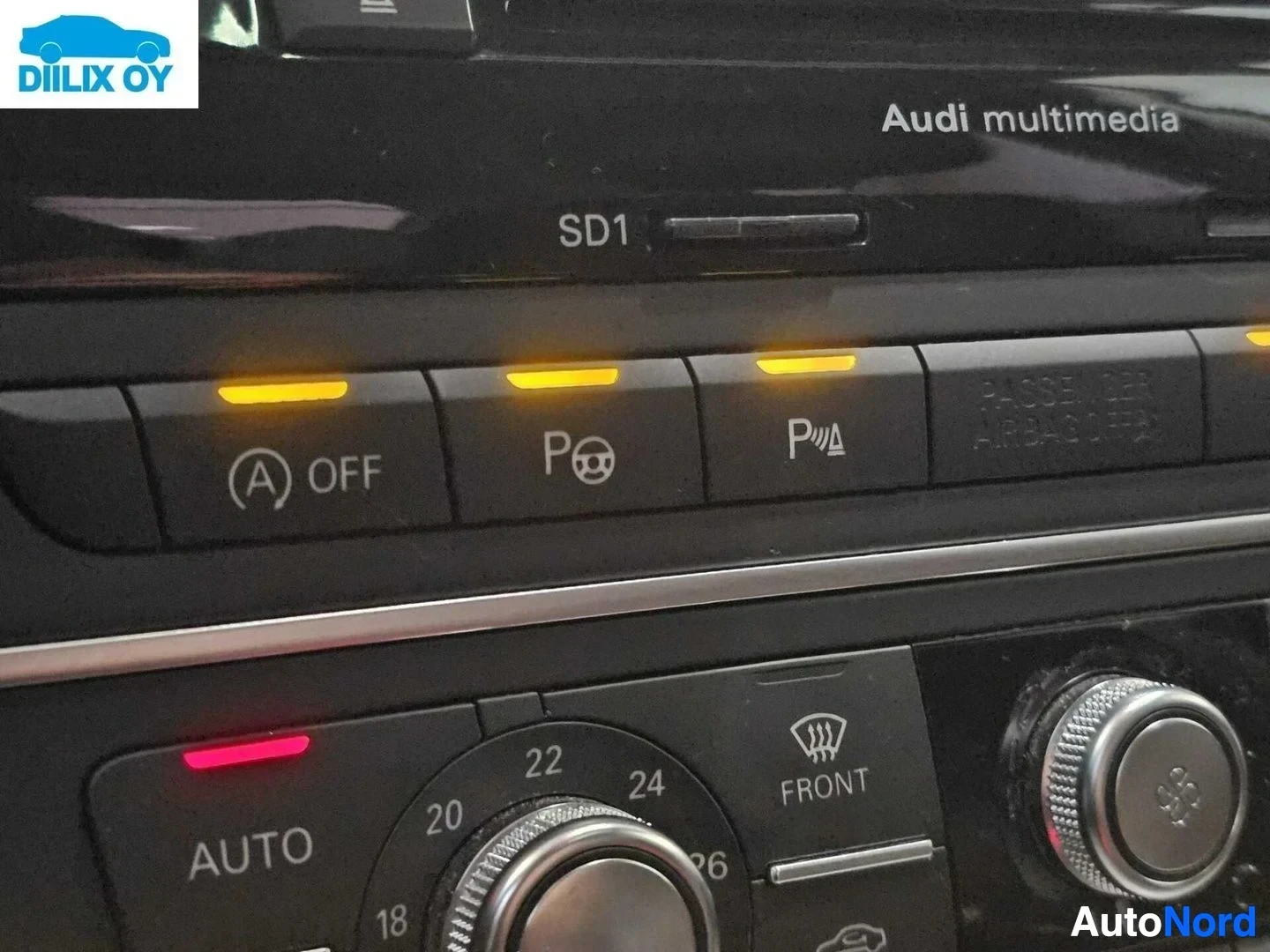 Yksityiskohta: Ohjauspaneelin yläosa näyttää Audi multimedia SD1 -järjestelmän, alla ilmastoinnin säätöpaneeli, jossa AUTO-painike ja lämpötilan ohjaus 18-26 °C, sekä painikke