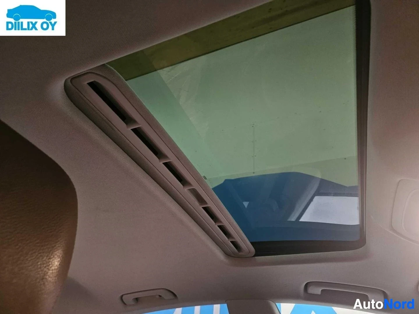 Ohjaamo: Auton sisätilassa panoraamakattoaukko, näkyvissä vaalea kangas ja tumma kehys.