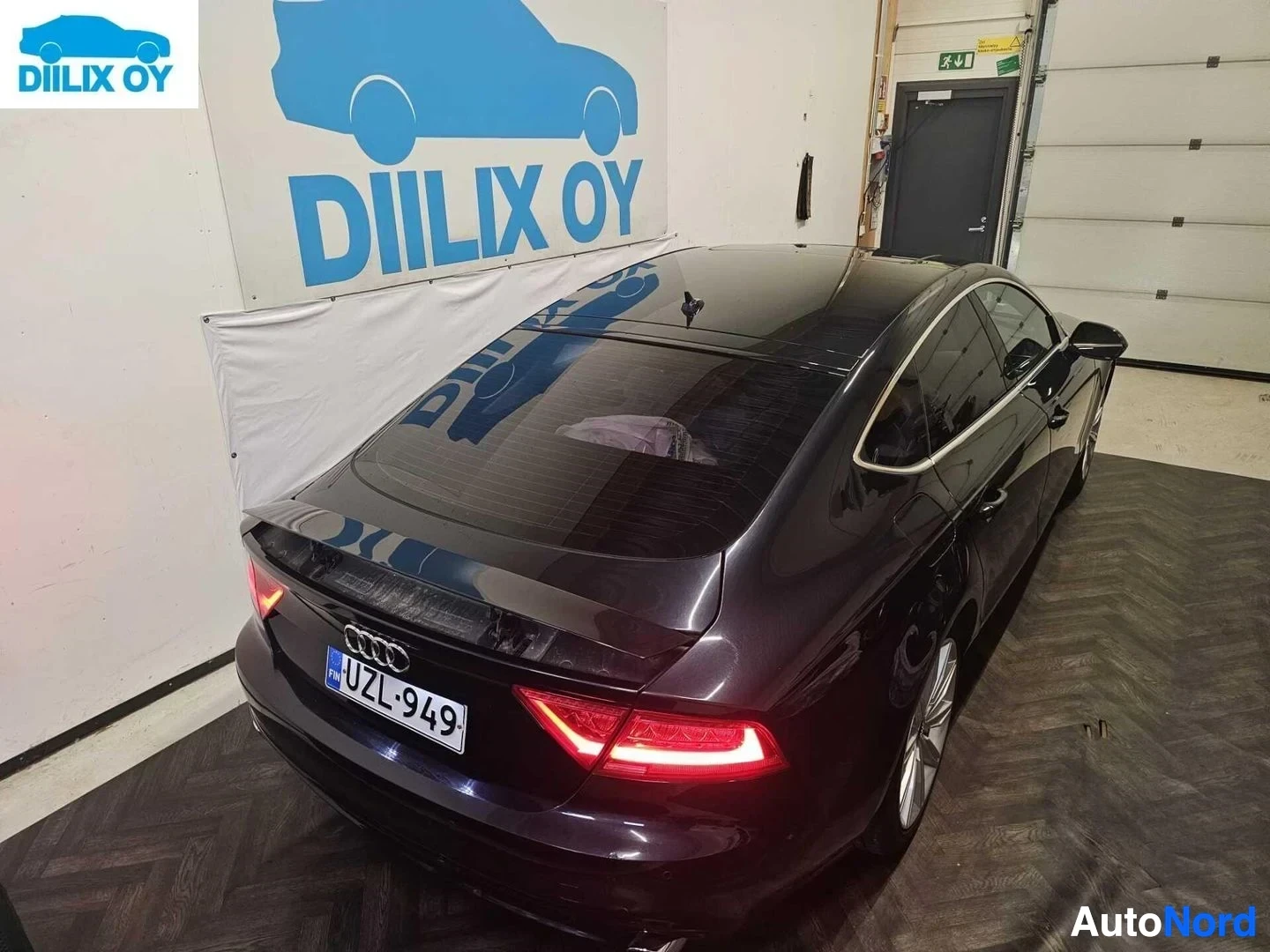 Takaa: Tummanpunainen Audi viistoperä sisätiloissa taakaa näkyvissä, LED-takavaloilla ja rekisterikilpillä