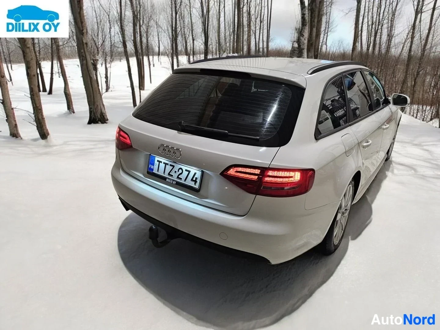 Takaa: Valkoinen Audi-farmari takaosasta kuvattuna, rekisterikilvessä, takaosassa vetolaitteella, lumisella alueella