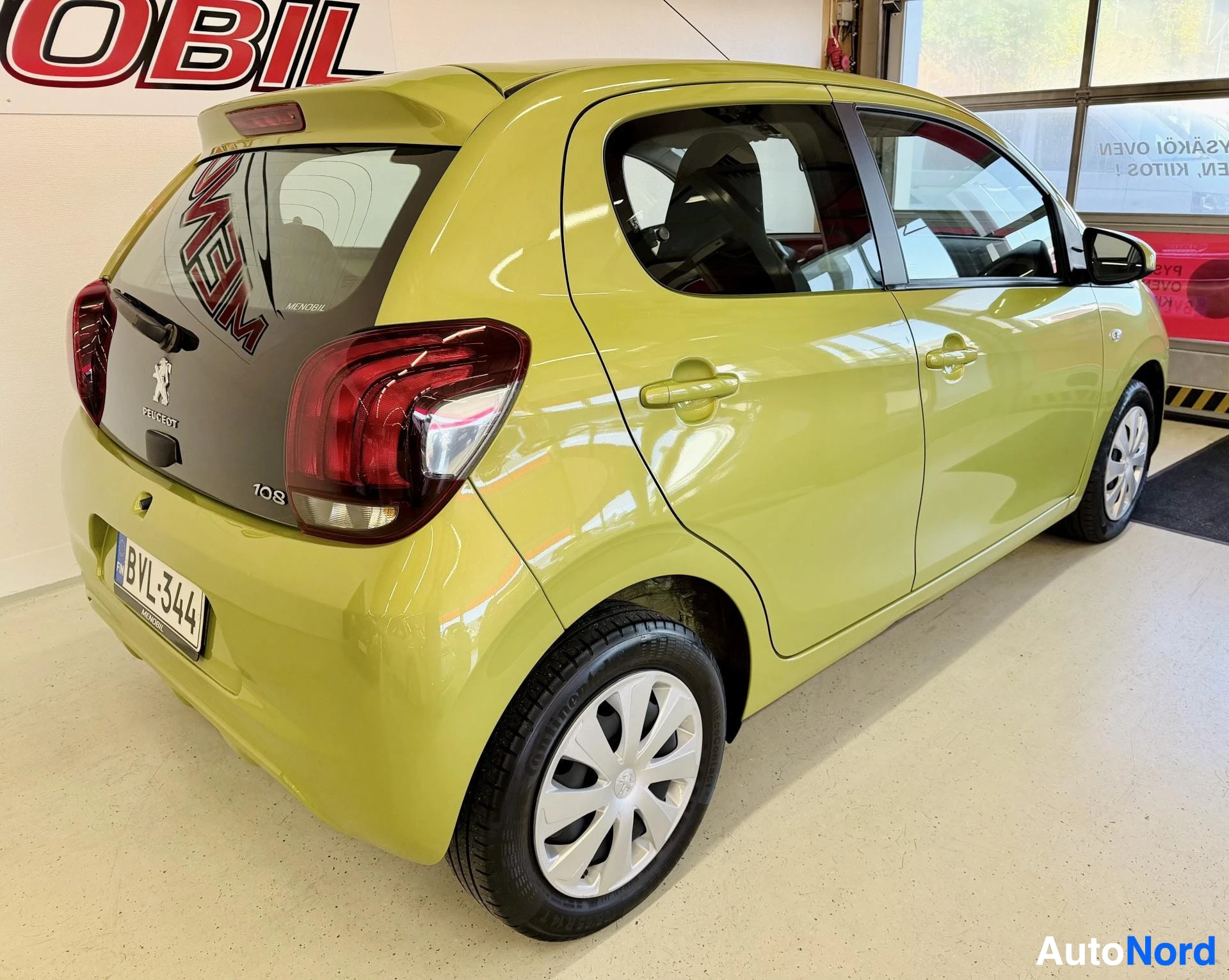 Takaviisto: Kuvassa vaaleanvihreä henkilöauto takavasemmalta kuvattuna. Autossa näkyy takavalot, Peugeot-logo ja "108"-merkintä. Rekisterikilpi "" on näkyvissä