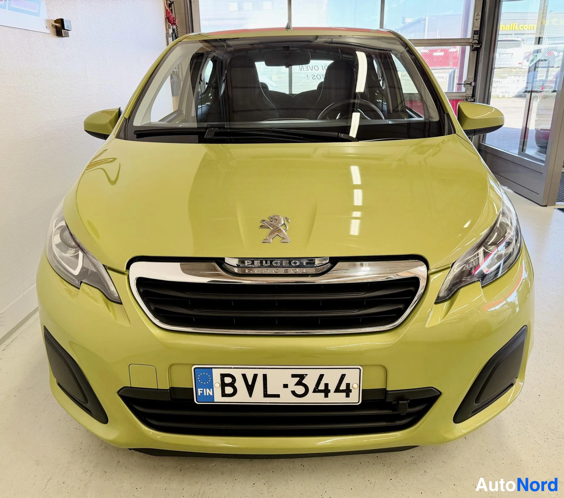 Edestä: Kuvassa vaaleanvihreä henkilöauto edestä päin. Etupuskurissa on Peugeot-logo ja rekisterikilpi ""