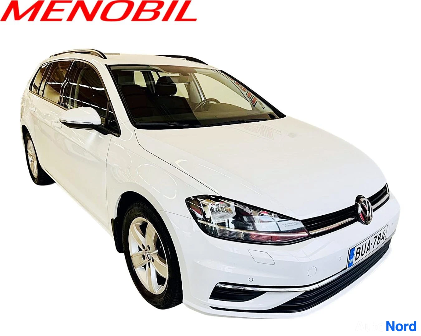 Etuviisto, nokka vasemmalle: Valkoinen Volkswagen Golf Variant kuvattuna edestä ja vasemmalta puolelta, nokka osoittaa kuvan vasempaan reunaan. Autossa on kattokaiteet ja parkkitut