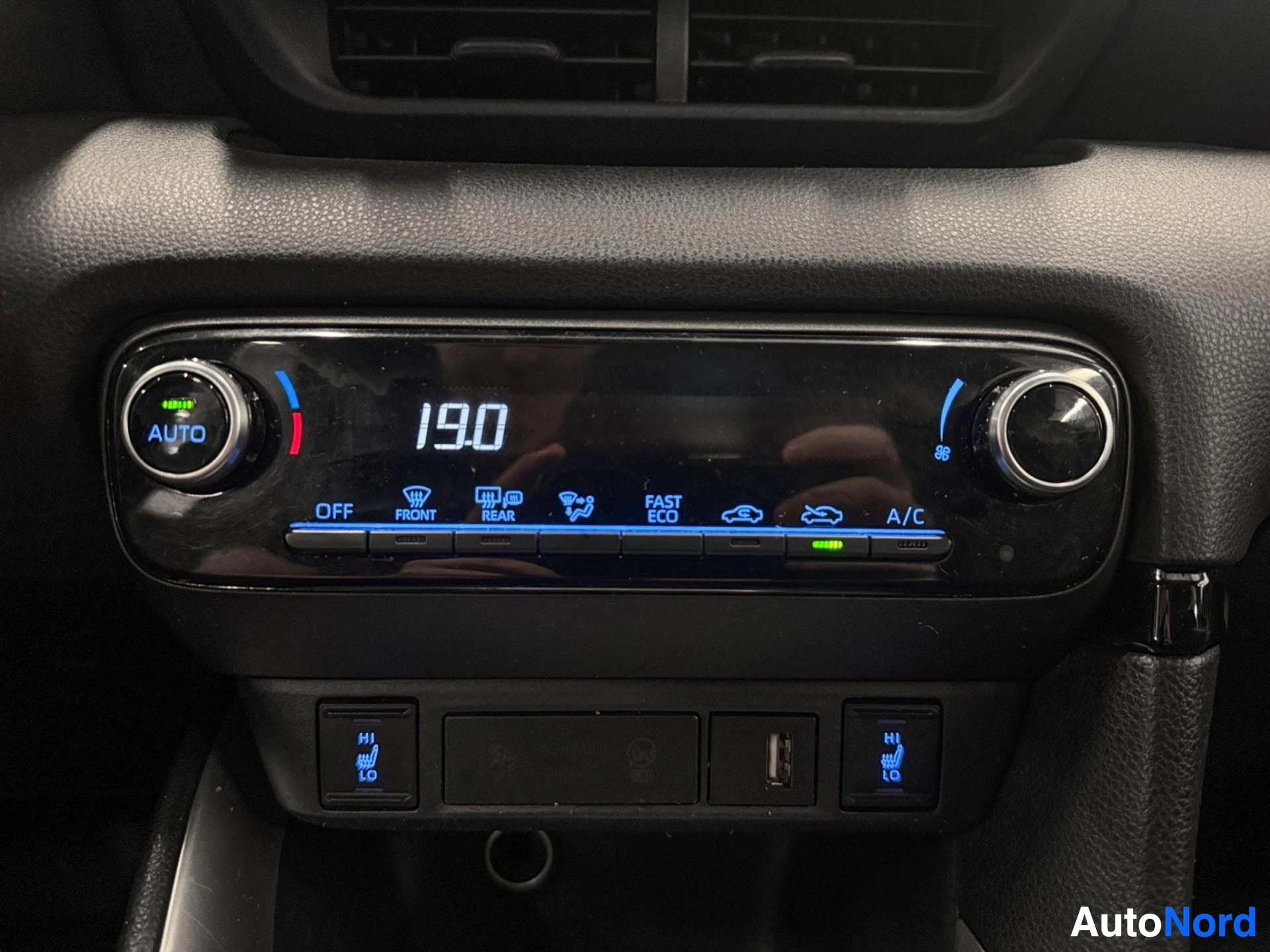 Yksityiskohta: Ilmastointi-ohjainpaneeli, jossa näkyy AUTO-asetus, lämpötila 19,0 astetta, FRONT, REAR, ECO ja FAST-näytöt sekä A/C-painike.