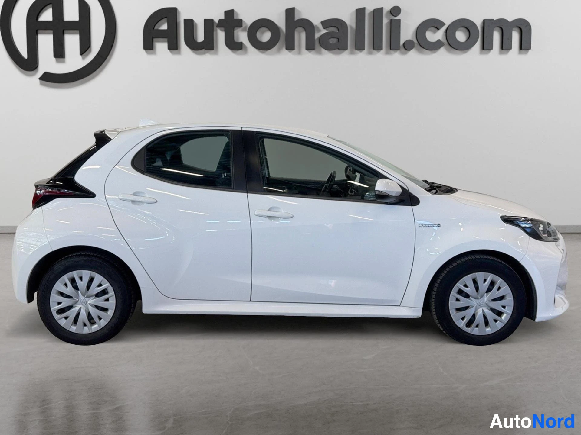 Sivulta: Valkoinen Toyota Yaris oikealta sivulta kuvattuna.
