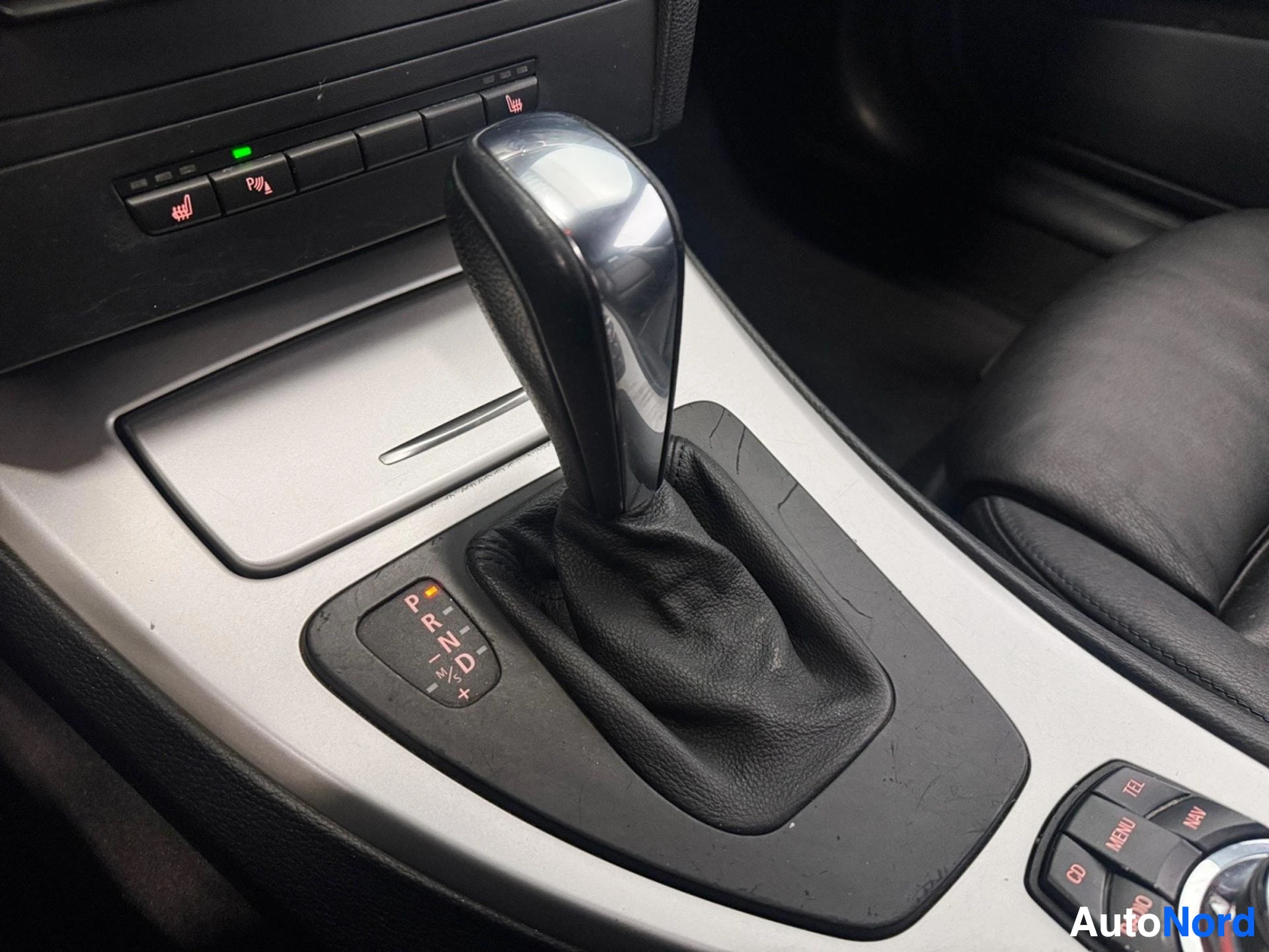Ohjaamo: Lähikuva auton automaattivaihteiston vaihteenvalitsimesta ja iDrive-ohjaimesta.