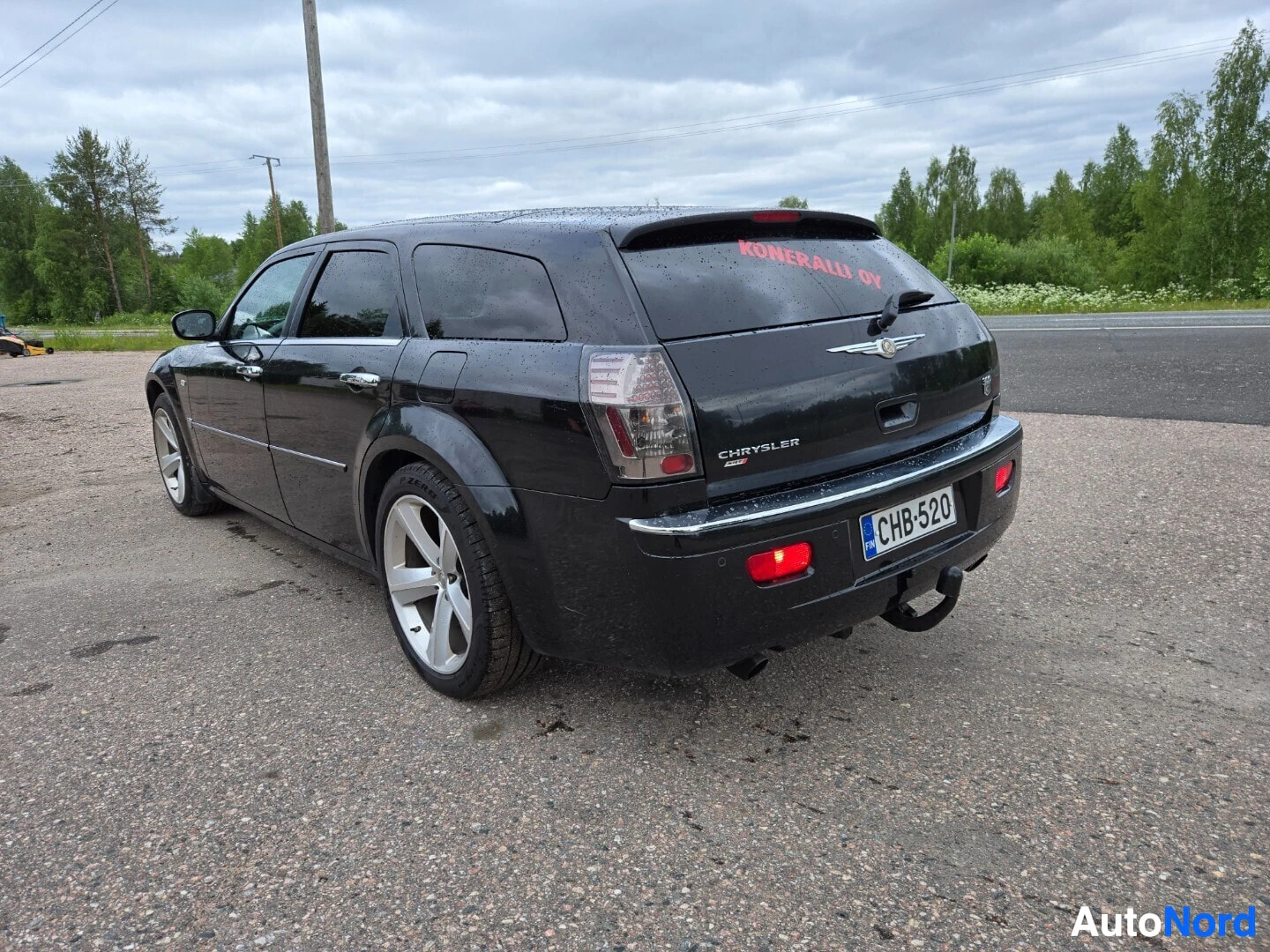 Takaviisto: Musta Chrysler 300C farmari perä vasemmalla puolella ja sivu oikealla, peräkoukku näkyvissä. Rekisterikilpi
