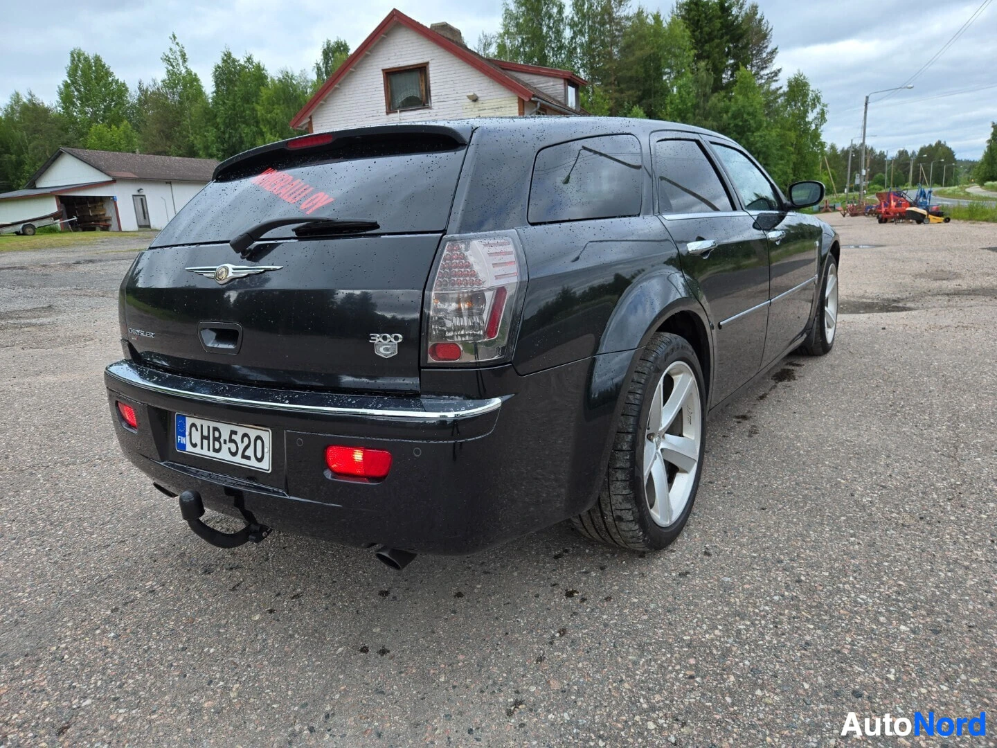 Takaviisto: Musta Chrysler 300C farmari oikealta takaviistosta, peräkoukku näkyvissä. Rekisterikilpi