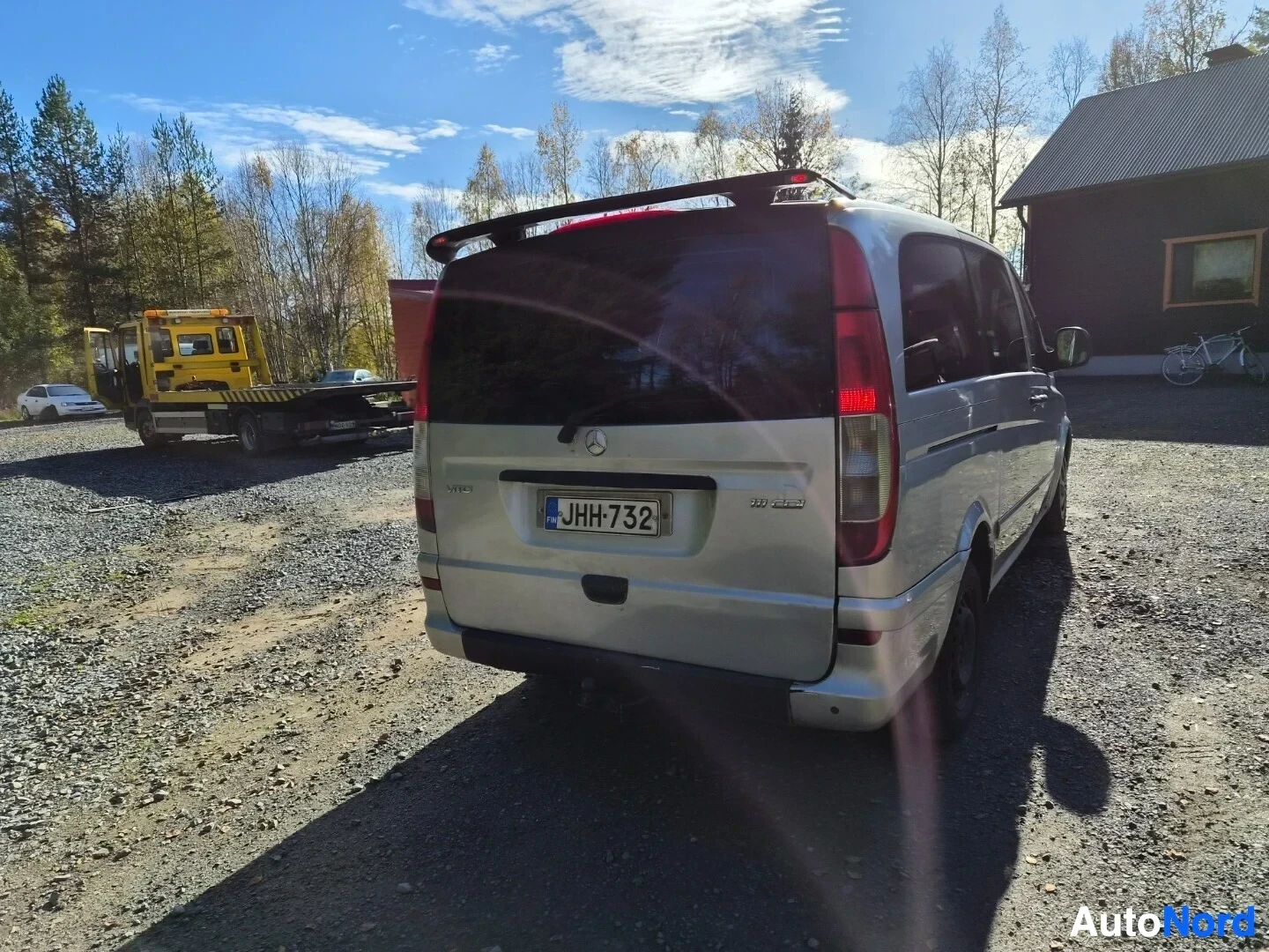 Takaviisto: Hopeanvärinen pakettiauto takaa oikealta kuvattuna. Rekisterikilpi on näkyvissä. Tummat takalasit ja spoileri takaluukussa