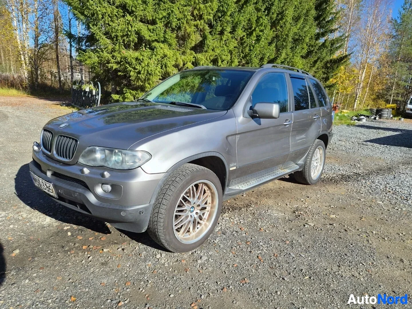 Etuviisto, nokka oikealle: Harmaa SUV oikeasta edestä kuvattuna soratiellä, auton oikea etukulma lähimpänä kameraa. Ajovalot, etusäleikkö, konepelti ja oikea kylki näkyvät. Katolla