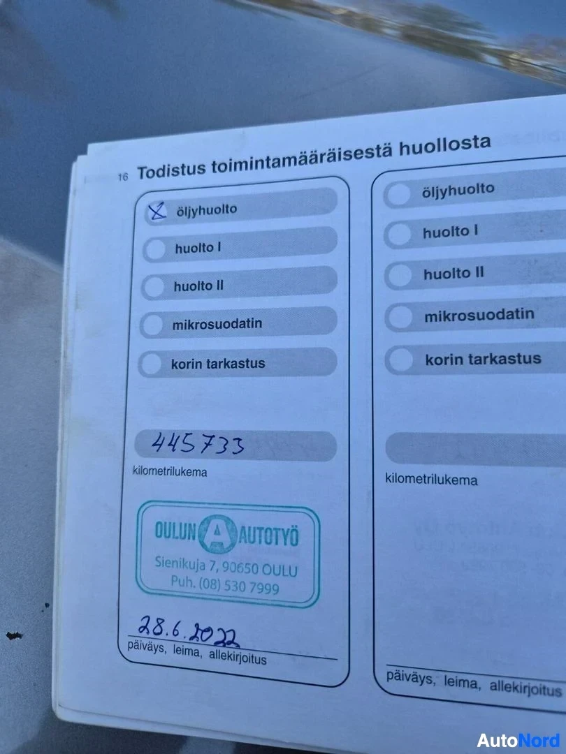 Asiakirja: Lähikuva avoinna olevan huoltokirjan sivusta, jossa on yksi täytetty huoltoleima. Tekstistä näkyy valittu 'Öljyhuolto', kilometrilukema 445733, huoltoliikkeen l