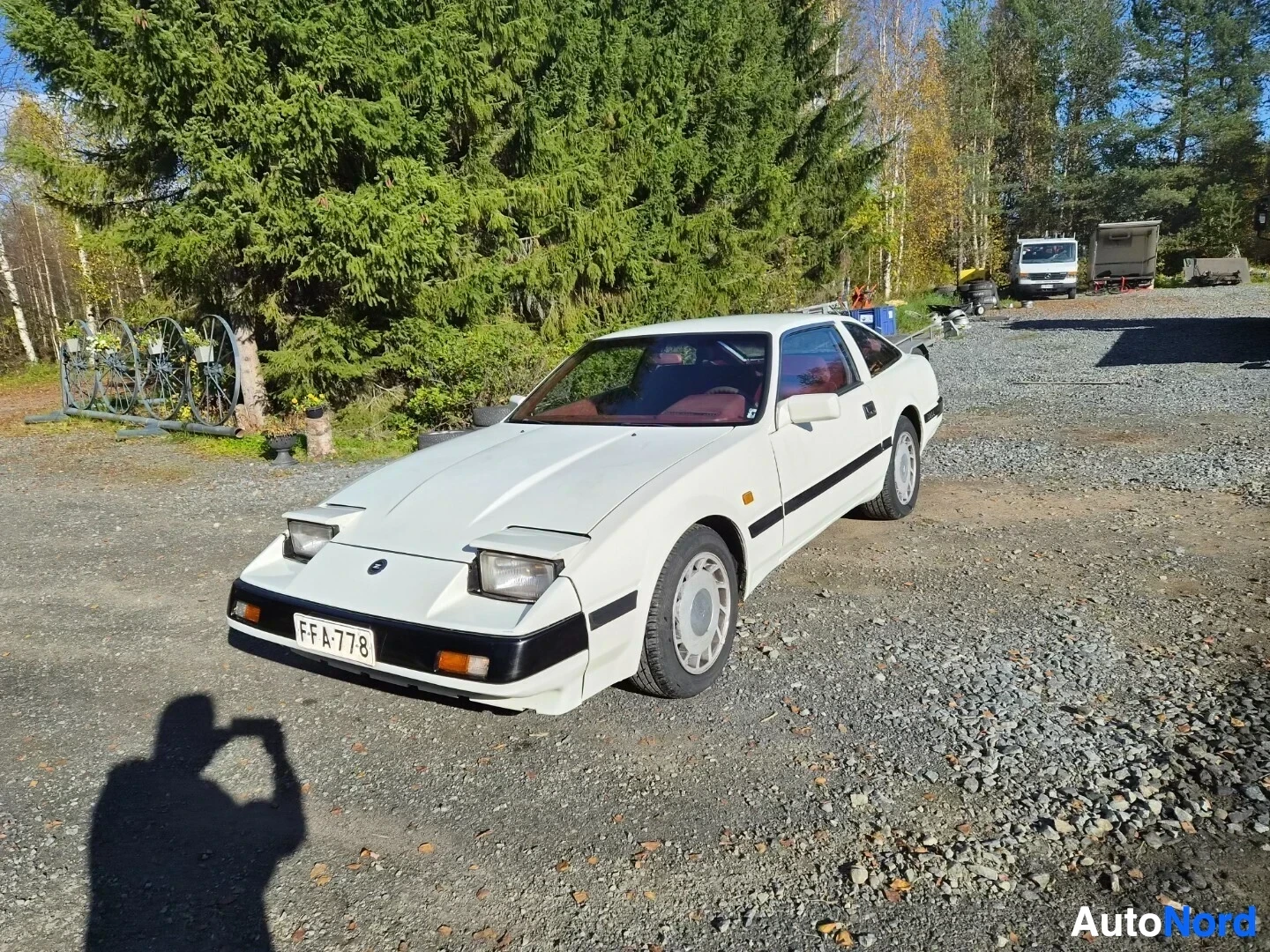 Etuviisto, nokka vasemmalle: Valkoinen Nissan 300ZX, rekisterikilpi, kuvattu edestäpäin hieman oikealta, kuljettajan puoleinen etupyörä näkyy selvästi. Ajovalot ovat ylös n