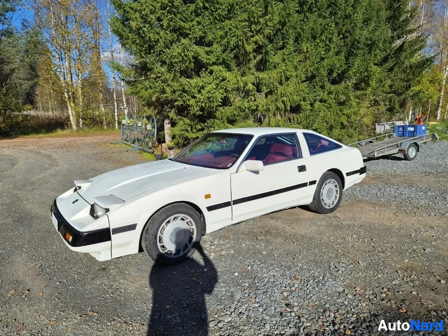 Etuviisto, nokka vasemmalle: Valkoinen Nissan 300ZX, rekisterikilpi, kuvattu edestäpäin hieman oikealta, kuljettajan puoli esillä. Ajovalot ovat ylös nostetussa asennossa