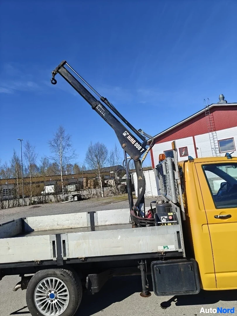 Etuviisto, nokka vasemmalle: Keltainen pakettiauto, jossa on nosturi lavalla. Ajoneuvon vasen kylki ja keula näkyvät. Nosturin varressa on tarra, jossa lukee "HIAB 008 T".