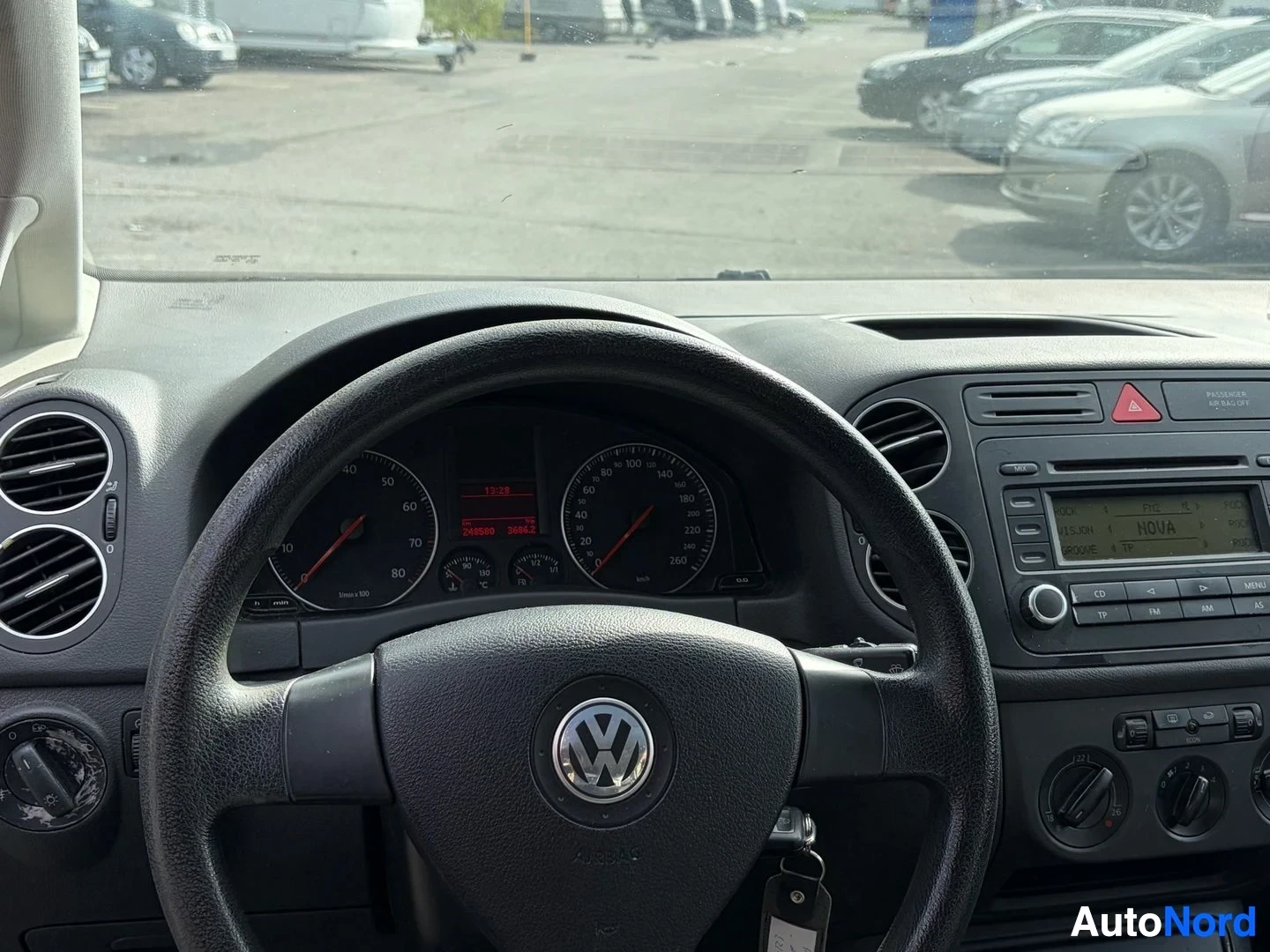 Ohjaamo: Kuvassa näkyy auton kojelauta ja ohjauspyörä suoraan edestäpäin. Mittariston näyttö on päällä, ja nopeusmittari näyttää lukemaa 0 km/h ja kierroslukumittari 0.