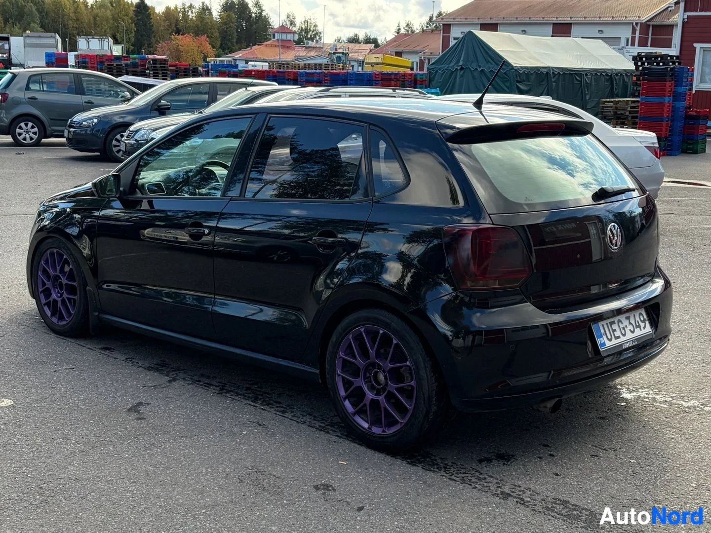Takaviisto: Musta auto parkkipaikalla takaapäin kuvattuna. Autossa on musta koripaneeli, tummennetut takaikkunat, takaspoileri, tummennetut takavalot ja violetit kevytmetal