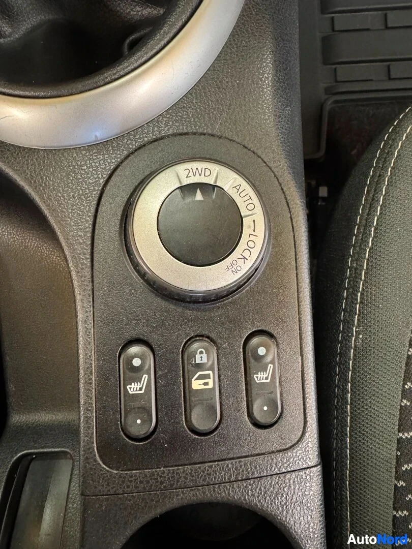 Yksityiskohta: Lähikuva keskikonsolin painikkeista, mukaan lukien nelivedon valitsin (2WD, Auto, Lock), keskuslukituspainike ja kaksi istuinlämmittimen ohjainta.