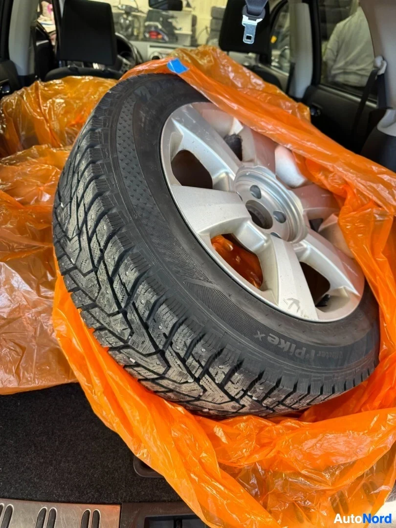 Tavaratila: Yksi nastarengas vanteella takakontissa oranssissa suojapussissa.