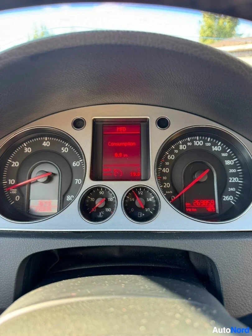Yksityiskohta: Ajoneuvon mittaristo ja keskellä näyttö, jossa teksti 'Consumption'. Näytössä lukema '8.9 l/100km'.