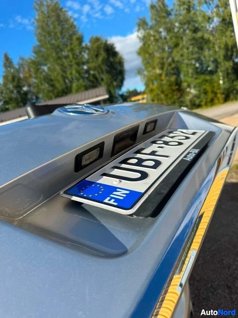 Yksityiskohta: Lähikuva auton takaosasta, jossa on rekisterikilpi ja teksti "FIN". Rekisterikilven yläpuolella on kaksi mustaa valaisinta ja auton takaluukun Volkswage