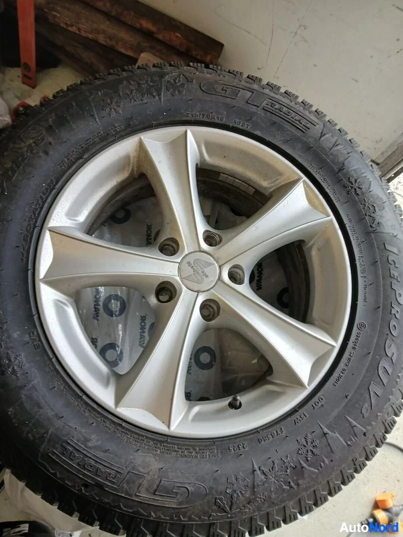 Yksityiskohta: Renkaan päältä otettu kuva, joka esittää hopeista viisipuolaista kevytmetallivannetta ja GT RADIAL ICEPRO SUV -nastarengasta. Renkaan kulutuspinnassa on nastoja