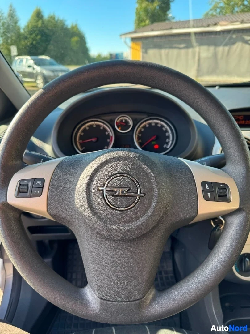 Ohjaamo: Kuvassa auton ohjauspyörä ja mittaristo. Ohjauspyörässä on monitoiminäppäimet vasemmalla ja oikealla puolella, ja keskellä on Opel-logo. Mittaristo näyttää kier