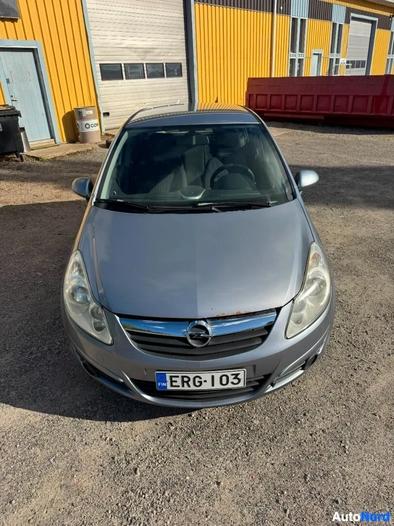 Edestä: Harmaa henkilöauto edestä, sen rekisterikilvessä on teksti