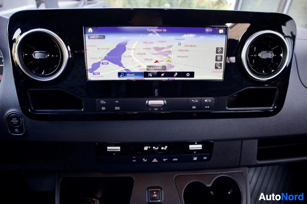 Yksityiskohta: Infotainment-näyttö näyttää navigointikartan ja keskikonsolissa on ilmastoinnin säätimet, joissa näkyy lämpötila 18 astetta.