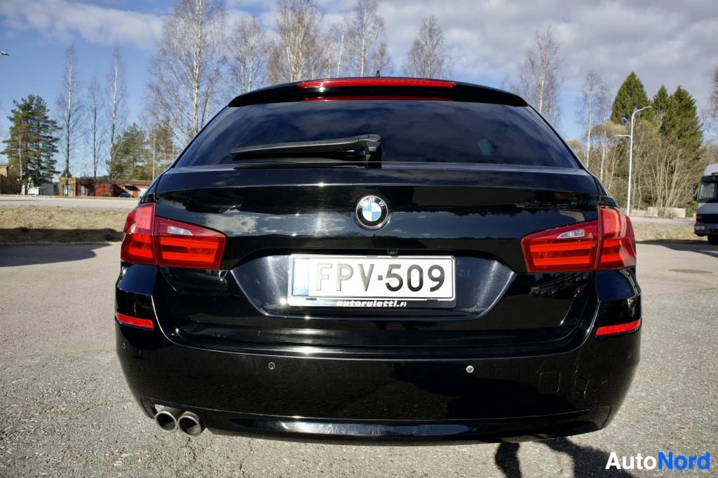 Takaa: Musta BMW 5-sarjan farmari kuvattuna suoraan takaa. Takaluukku, takavalot ja rekisterikilpi "" ovat näkyvissä. Takapuskurin alaosassa on kaksi pyöreää pakoputke