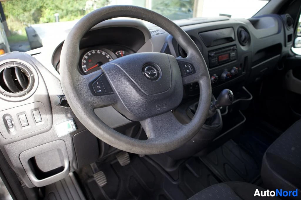 Ohjaamo: Ajoneuvon sisätilan kuva näyttää ohjaamon, jossa on monitoimiohjauspyörä Opel-logolla. Mittaristo ja vaihdekeppi ovat myös näkyvissä. Ilmastointilaite on näkyvi