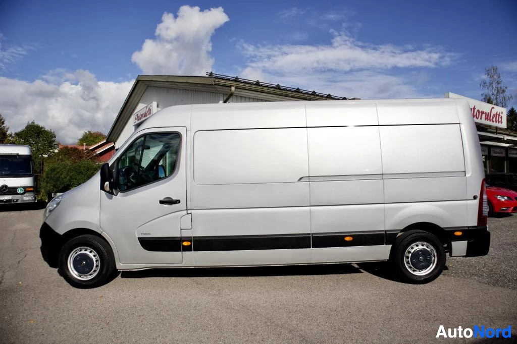 Sivulta: Ajoneuvon vasen sivu kuvattuna ulkona. Ajoneuvo on pakettiauto, jossa on umpinaiset kyljet ja takaovet.