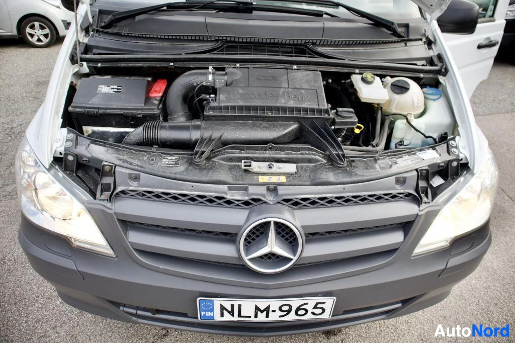Moottoritila: Lähikuva avatusta konepellistä, jossa näkyy auton moottoritila, musta Mercedes-Benz-logo konepellin alaosassa ja rekisterikilpi "".