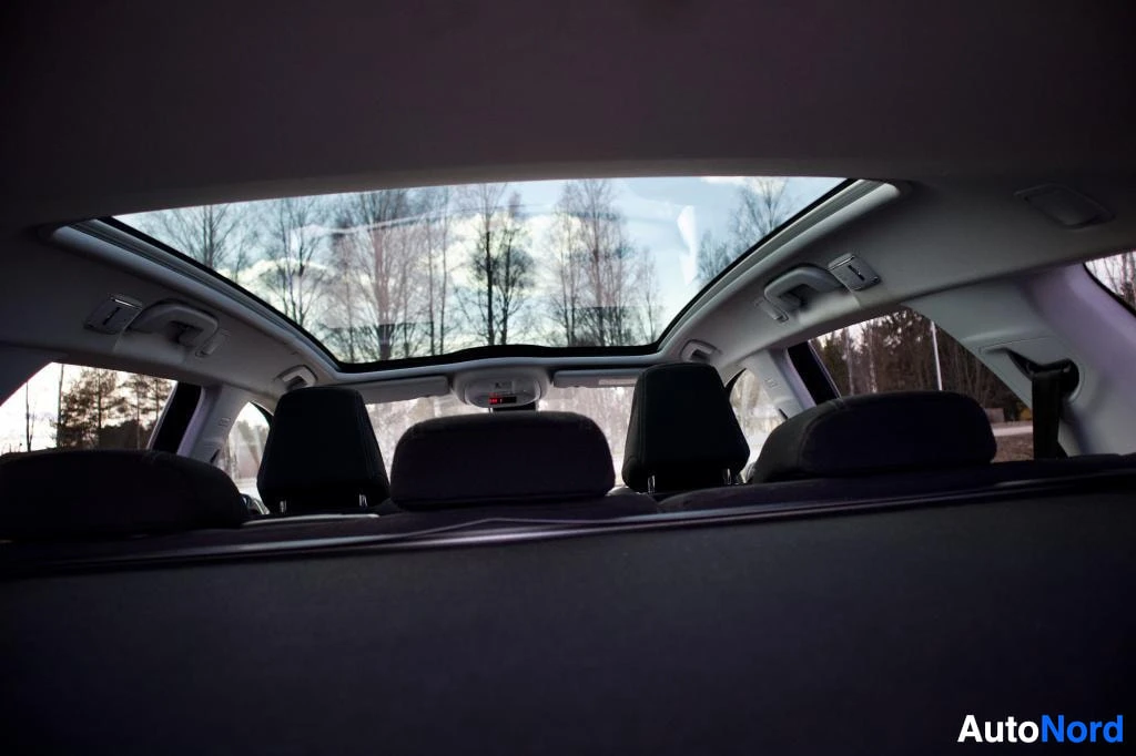 Ohjaamo: Kuvakulma tavaratilasta eteenpäin, näyttäen auton sisätilan ja panoraamalasikaton. Takapenkkien niskatuet ovat näkyvillä.