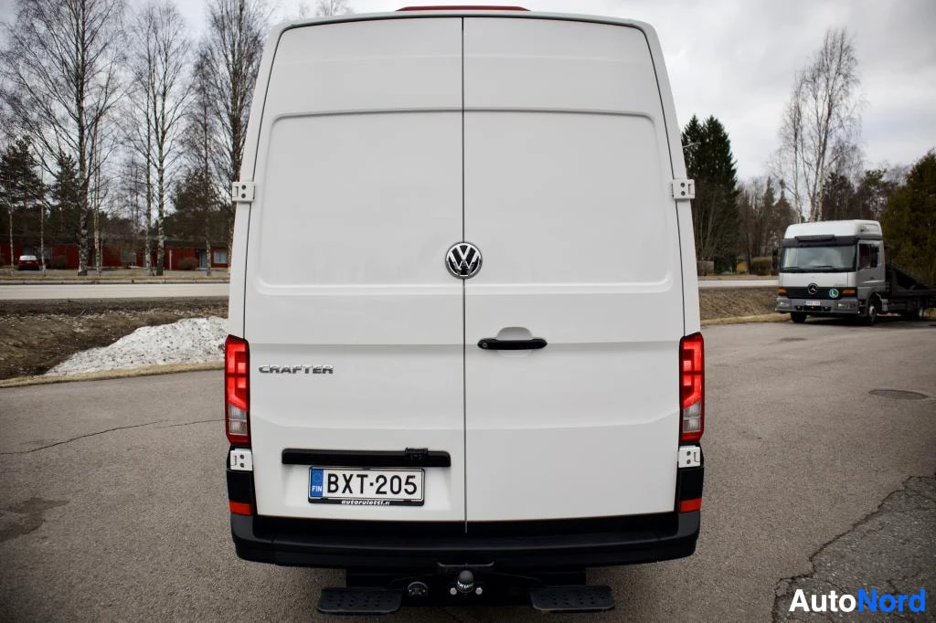 Takaa: Valkoinen pakettiauto takaa kuvattuna. Takaovet, takavalot ja rekisterikilpi ovat näkyvissä. Takapuskurissa on vetokoukku ja kaksi astinlautaa.