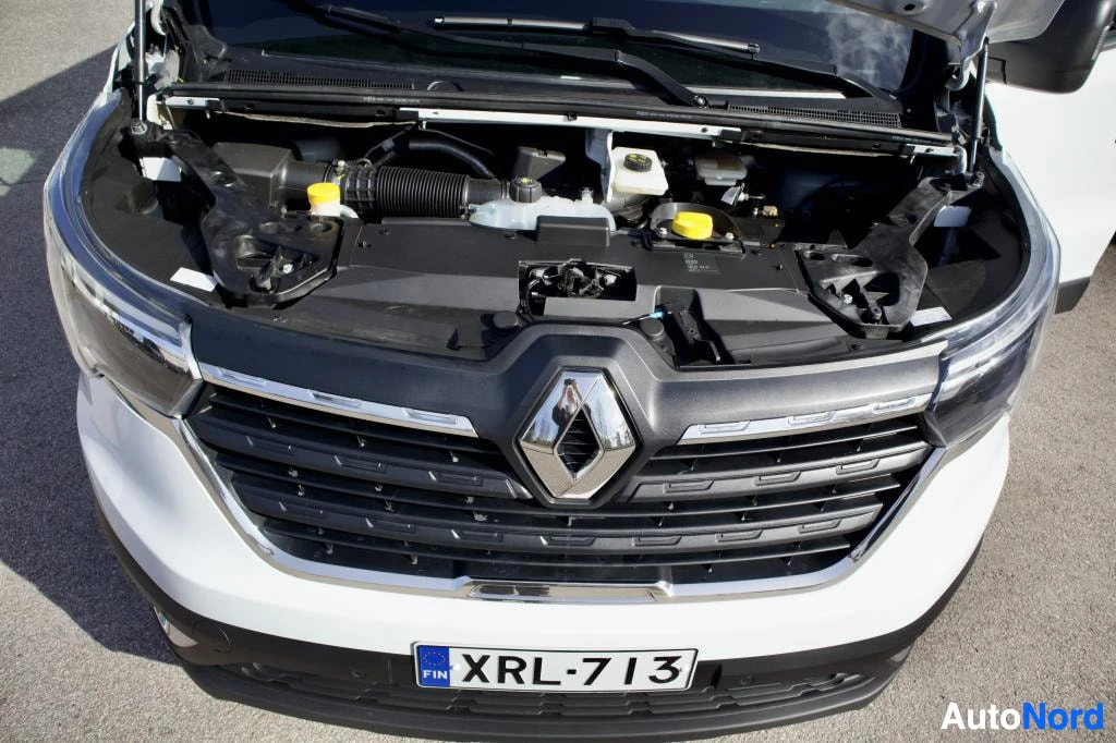 Moottoritila: Ajoneuvon etuosa konepelti avattuna, näyttäen moottoritilan osia, etusäleikön ja Renault-logon.