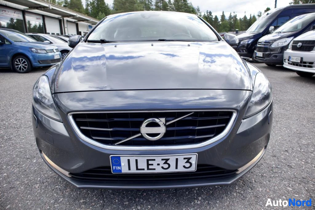 Edestä: Harmaa henkilöauto edestä päin kuvattuna. Ajoneuvossa on suomalainen rekisterikilpi tekstillä.