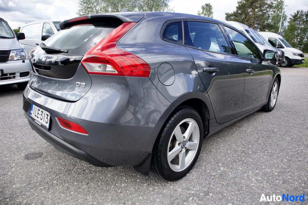 Takaviisto: Harmaa Volvo V40 auton takakulmasta kuvattuna, ajoneuvon rekisterikilvessä on teksti "".