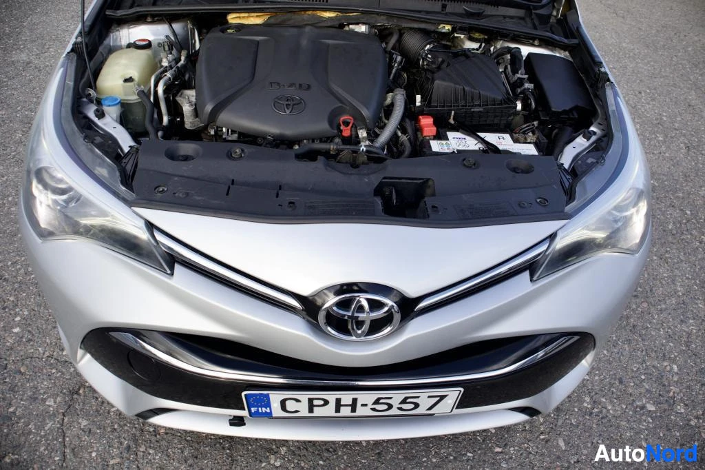 Edestä: Konepelti auki, moottori näkyvissä. Keulassa hopeinen Toyota-logo ja etupuskurissa suomalainen rekisterikilpi